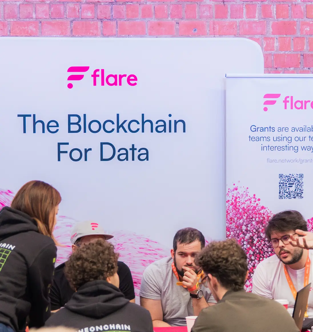 Group of people sit in front of sign with Flare logo that says The Blockchain For Data